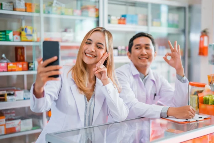 Zwei junge Apotheker:innen machen ein Selfie in der Offizin – Employer Branding in der Apotheke über Social Media