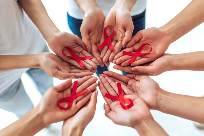 Mehrere Hände in einem Kreis halten rote Schleifen – Symbol für HIV/AIDS-Bewusstsein.