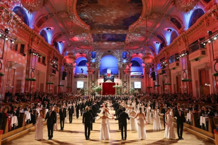 Eröffnung eines festlichen Balls in einem prunkvollen Saal mit Kronleuchtern, in dem viele Paare in Abendkleidung und weißen Ballkleidern Walzer tanzen.