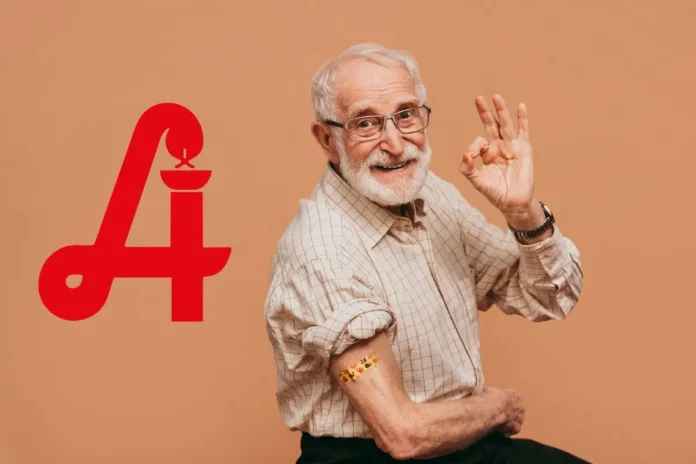 Älterer Mann mit Pflaster am Oberarm nach einer Impfung, lächelt und zeigt eine Okay-Geste; daneben ein großes rotes „A“ mit Kerzensymbol.