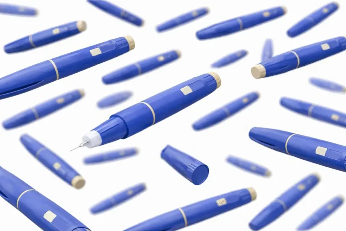 Mehrere blaue Insulinpens mit sichtbarer Nadel schweben vor weißem Hintergrund.