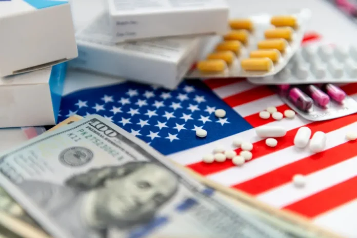 Verschiedene Medikamente in Blisterpackungen und Schachteln liegen auf einer US-Flagge neben US-Dollar-Scheinen.