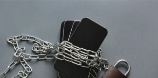 Mehrere Smartphones sind mit einer Metallkette umwickelt und mit einem Vorhängeschloss gesichert.