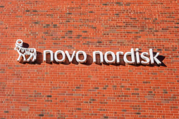 Weißes „Novo Nordisk“-Logo an einer roten Backsteinwand.
