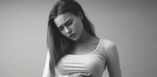 Junge Frau hält sich den Bauch und wirkt schmerzgeplagt.