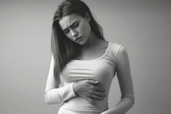 Junge Frau hält sich den Bauch und wirkt schmerzgeplagt.
