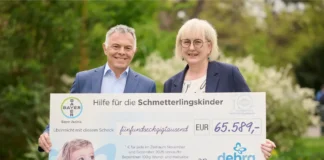 Zwei Personen überreichen symbolischen Scheck über 65.589 Euro von Bayer Austria an DEBRA Austria für Menschen mit Epidermolysis bullosa