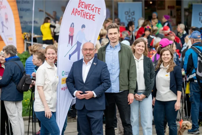 Teilnehmende beim Auftakt der Bewegten Apotheke in Hernals mit Nordic Walking vor einer Apotheke