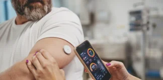 Mann mit Glukosesensor am Arm und Smartphone-App zur Blutzuckermessung