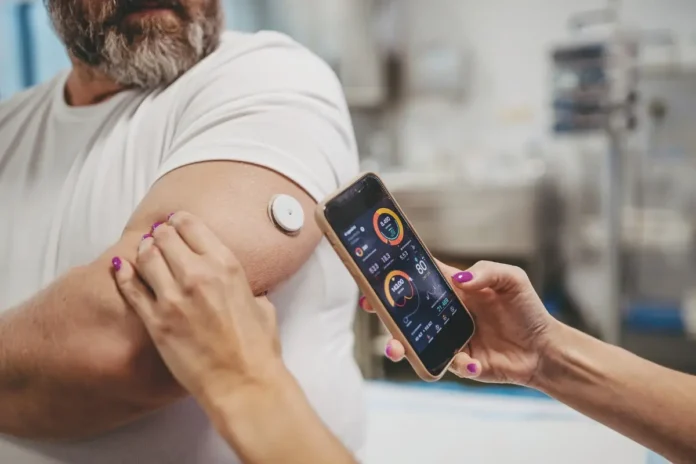 Mann mit Glukosesensor am Arm und Smartphone-App zur Blutzuckermessung