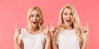 Zwei Frauen sehen sich sehr ähnlich und zeigen überrascht nach oben – Symbolbild für vermeintliche Doppelgänger