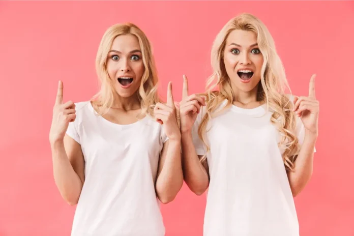 Zwei Frauen sehen sich sehr ähnlich und zeigen überrascht nach oben – Symbolbild für vermeintliche Doppelgänger
