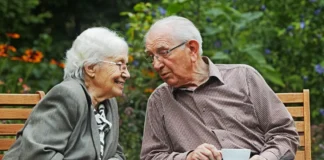 Älteres Paar über 80 sitzt auf einer Gartenbank und spricht miteinander