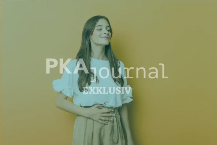 Frau mit entspanntem Gesichtsausdruck hält sich den Bauch – Symbol für Linderung von Magen-Darm-Beschwerden durch Kümmel