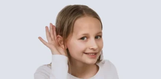 Kind hält Hand ans Ohr und hört aufmerksam, Symbolbild für Hörprobleme und Tinnitus bei Kindern
