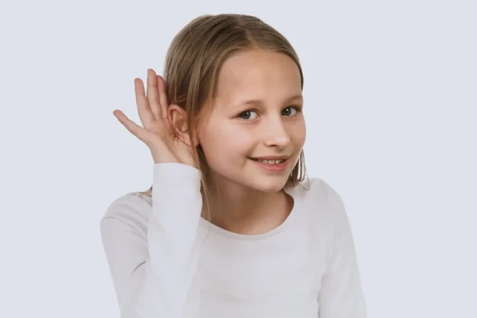 Kind hält Hand ans Ohr und hört aufmerksam, Symbolbild für Hörprobleme und Tinnitus bei Kindern