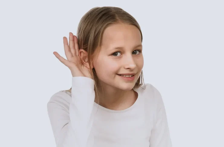 Kind hält Hand ans Ohr und hört aufmerksam, Symbolbild für Hörprobleme und Tinnitus bei Kindern
