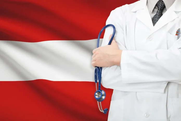 Arzt mit Stethoskop vor österreichischer Flagge als Symbol für das Gesundheitssystem in Österreich