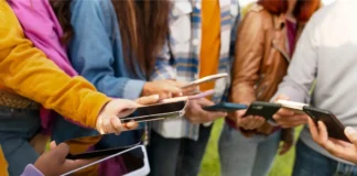 Jugendliche halten Smartphones in den Händen und stehen in einer Gruppe zusammen