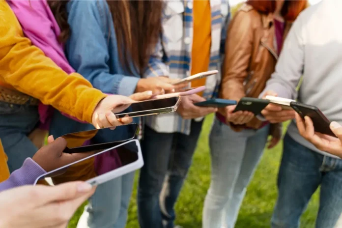 Jugendliche halten Smartphones in den Händen und stehen in einer Gruppe zusammen