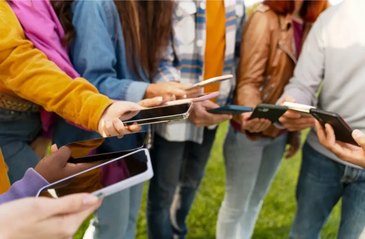 Jugendliche halten Smartphones in den Händen und stehen in einer Gruppe zusammen