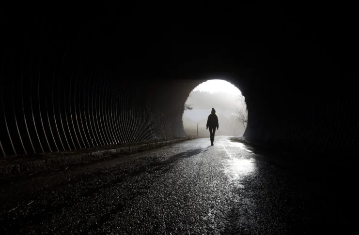 Silhouette einer Person am Ausgang eines Tunnels als Symbolbild für psychische Erkrankungen und mentale Gesundheit