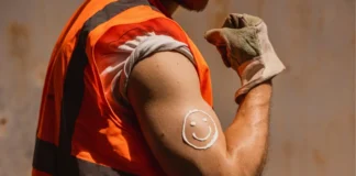 Arbeiter im Freien trägt Sonnenschutz auf den Arm auf, um sich vor UV-Strahlung und Hautkrebs zu schützen