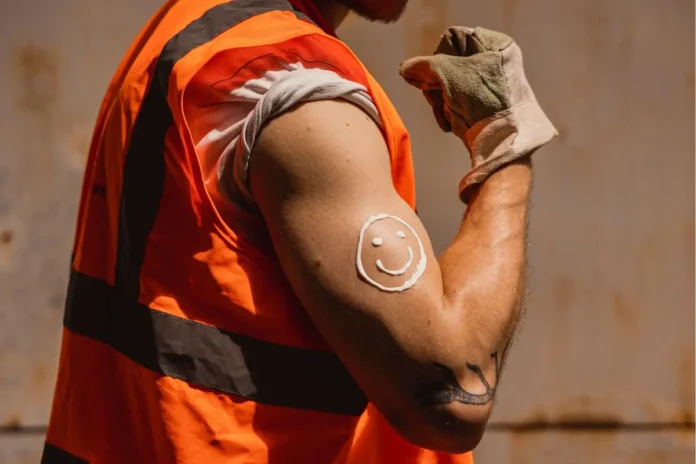 Arbeiter im Freien trägt Sonnenschutz auf den Arm auf, um sich vor UV-Strahlung und Hautkrebs zu schützen