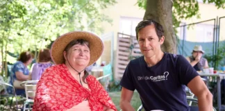 Besucherinnen und Besucher einer Caritas-Klimaoase nutzen einen schattigen Aufenthaltsbereich während einer Hitzewelle in Österreich.