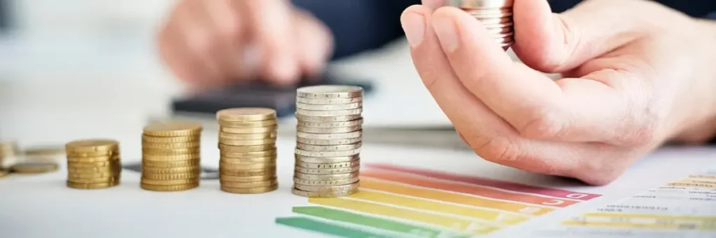 Münzstapel und Energieeffizienz-Skala als Symbol für steigende Energiekosten und Einsparpotenziale in Apotheken.