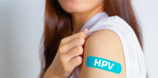 Frau mit Pflaster am Oberarm mit der Aufschrift HPV als Symbolbild für die HPV-Impfung und Krebsprävention.