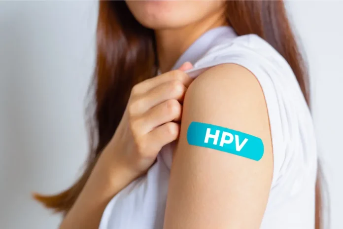 Frau mit Pflaster am Oberarm mit der Aufschrift HPV als Symbolbild für die HPV-Impfung und Krebsprävention.