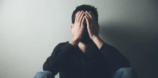 Mann sitzt am Boden und hält sich verzweifelt den Kopf – Symbolbild für psychische Erkrankungen in Österreich