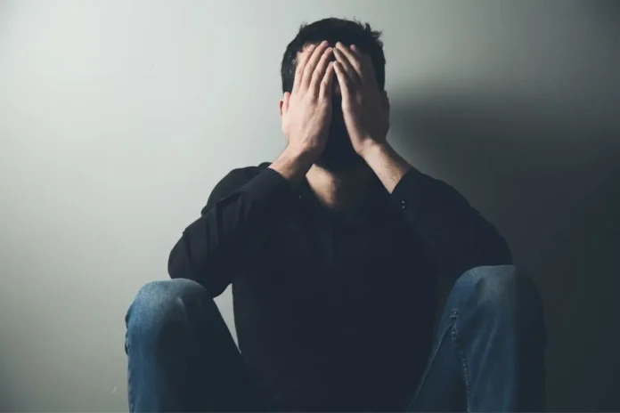 Mann sitzt am Boden und hält sich verzweifelt den Kopf – Symbolbild für psychische Erkrankungen in Österreich