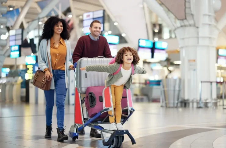 Familie mit Reisegepäck am Flughafen – e-card und Europäische Krankenversicherungskarte bieten Versicherungsschutz im Ausland.