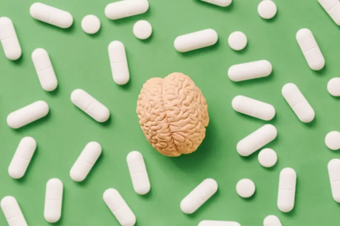 Modell eines Gehirns umgeben von Tabletten als Symbolbild für den Placeboeffekt und die Schmerzlinderung.