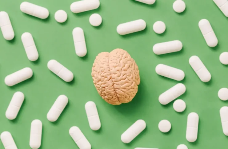 Modell eines Gehirns umgeben von Tabletten als Symbolbild für den Placeboeffekt und die Schmerzlinderung.