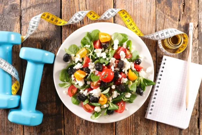 Salat mit Hanteln und Maßband als Symbol für Prävention durch Ernährung und Bewegung.