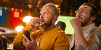 Fans verfolgen ein Fußballspiel in einem Lokal. Suchtexperten warnen, dass Sportwetten während großer Turniere problematisches Wettverhalten verstärken können.
