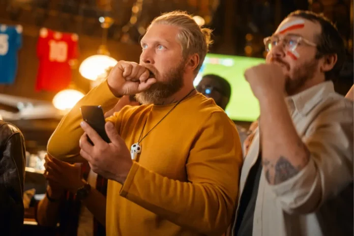 Fans verfolgen ein Fußballspiel in einem Lokal. Suchtexperten warnen, dass Sportwetten während großer Turniere problematisches Wettverhalten verstärken können.