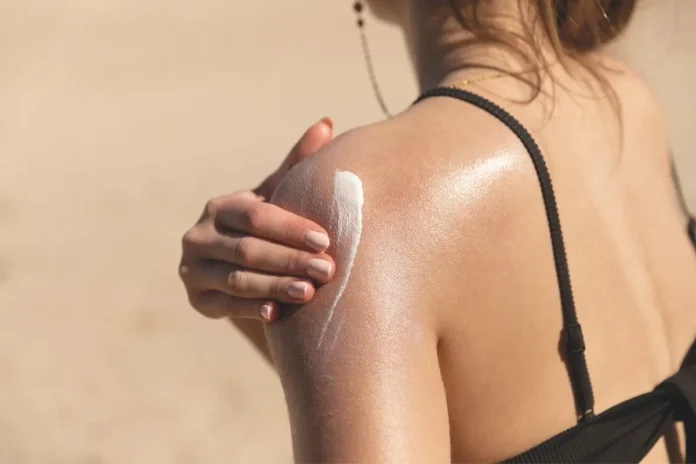Person trägt Sonnencreme auf die Schulter auf – umweltfreundlicher Sonnenschutz schützt Haut und Korallenriffe.