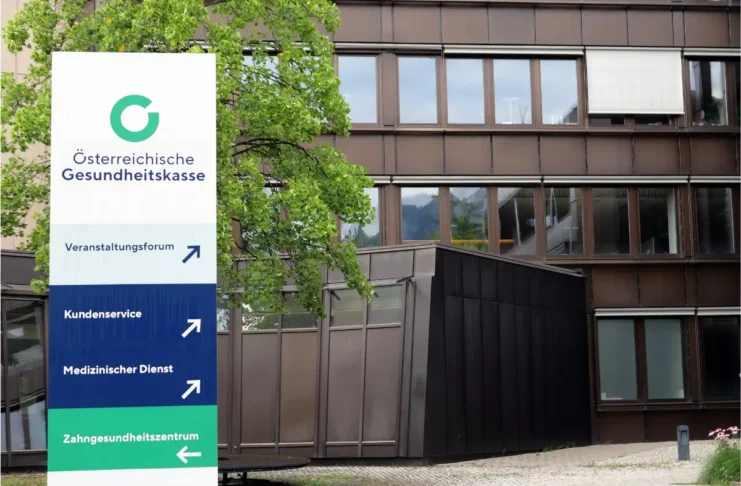 Schild der Österreichischen Gesundheitskasse vor einem ÖGK-Gebäude