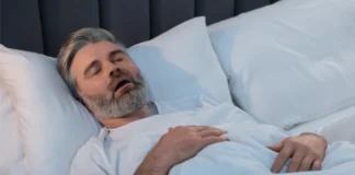 Schlafender Mann mit geöffnetem Mund im Bett als Symbolbild für obstruktive Schlafapnoe
