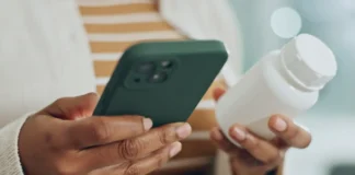 Person mit Smartphone und Medikamentenbehälter