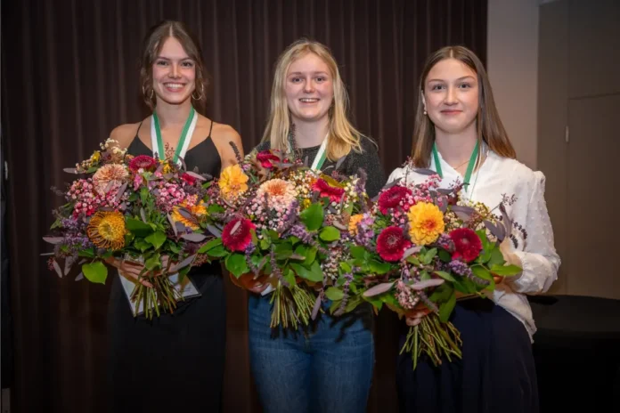 Die Siegerinnen des PKA-Bundeslehrlingswettbewerbs 2026: Leonie Weißbacher (Mitte), Laura Eder (links) und Annalena Hemetsberger (rechts) mit Blumensträußen und Medaillen.