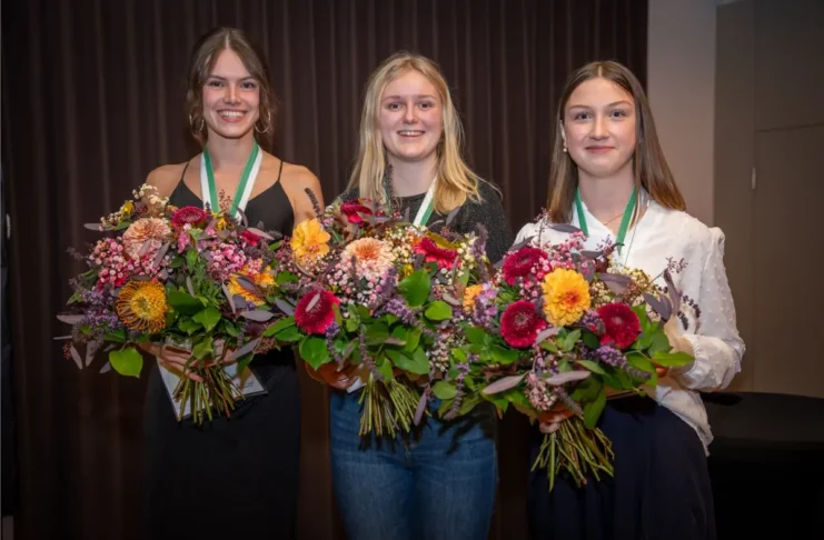 Die Siegerinnen des PKA-Bundeslehrlingswettbewerbs 2026: Leonie Weißbacher (Mitte), Laura Eder (links) und Annalena Hemetsberger (rechts) mit Blumensträußen und Medaillen.