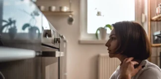 Frau sitzt vor einem Backofen in einer Küche – Symbolbild für Zwangsstörungen.